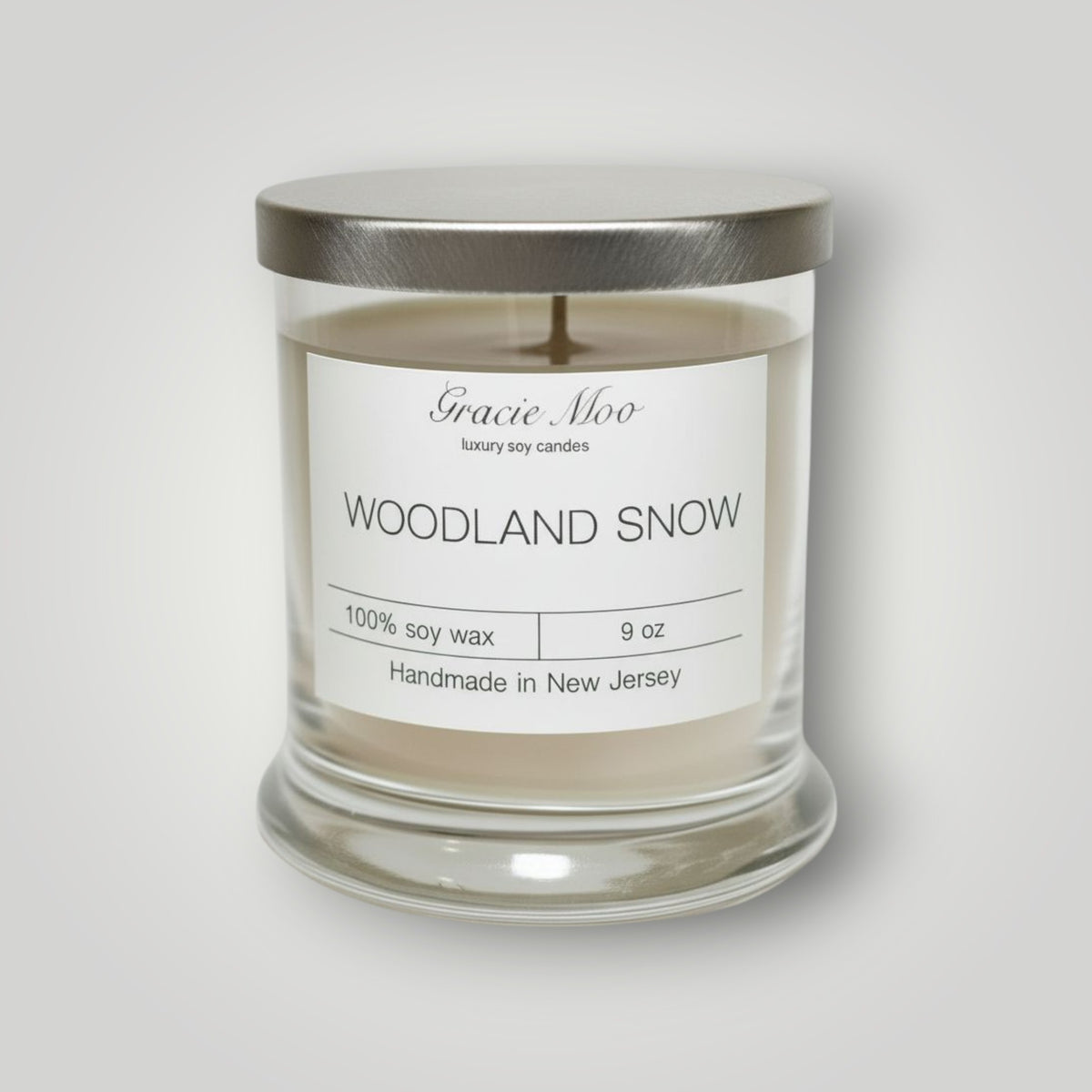 Woodland Snow Status Candle by Gracie Moo Candles featuring a cozy winter woodland scene on a white wax candle.