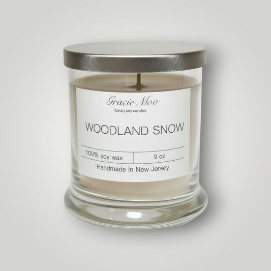 Woodland Snow Status Candle by Gracie Moo Candles featuring a cozy winter woodland scene on a white wax candle.