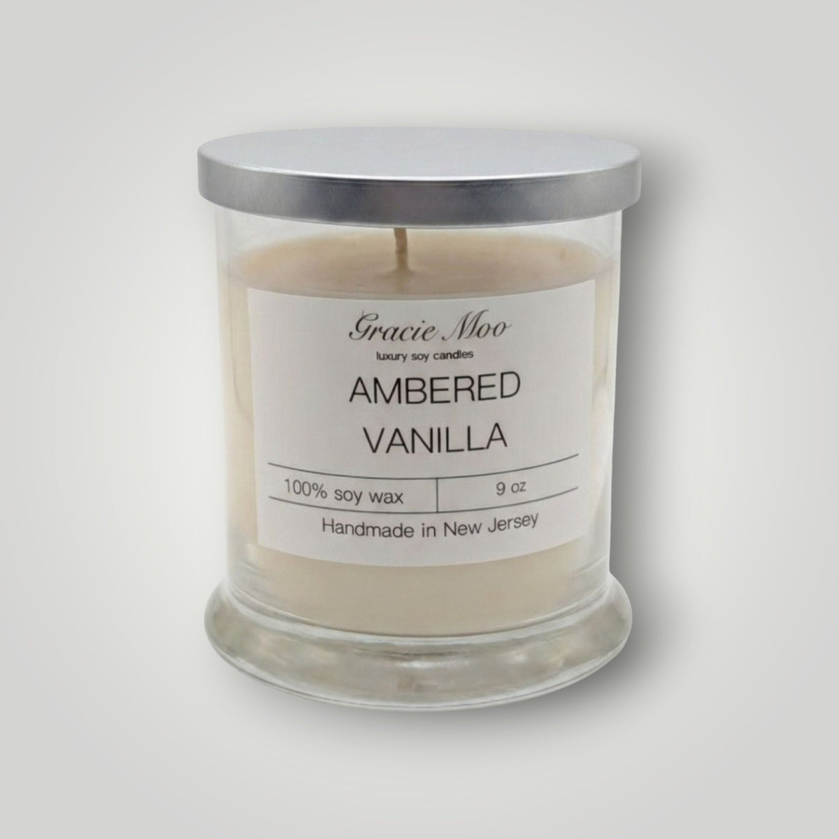Ambered Vanilla Status Candle by GracieMoo Candles, featuring a warm amber-colored glass container with a lit vanilla-scented flame.