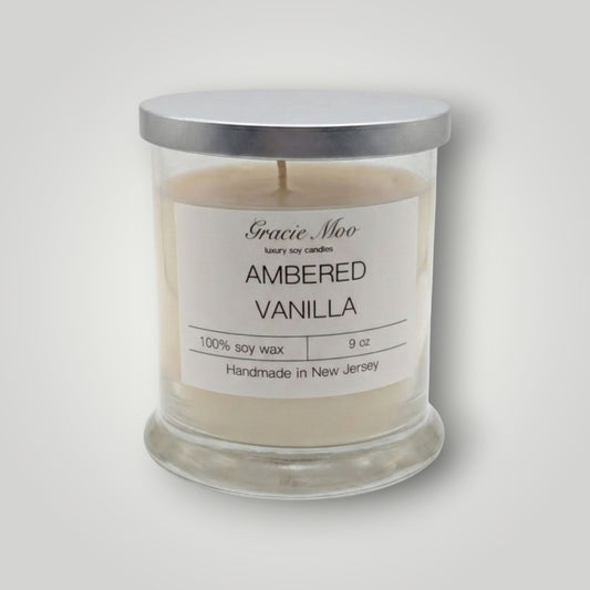 Ambered Vanilla Status Candle by GracieMoo Candles, featuring a warm amber-colored glass container with a lit vanilla-scented flame.