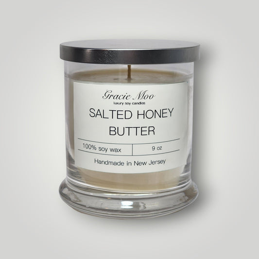 Gracie Moo Candles salted honey butter scented candle in a glass jar with a wooden wick and warm, inviting glow.