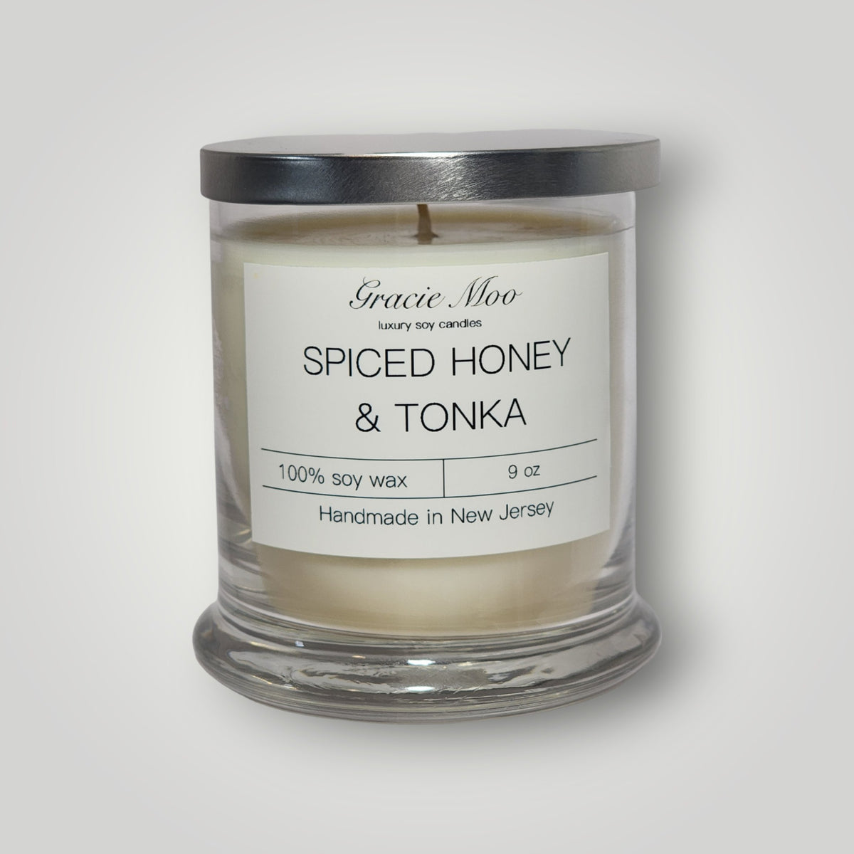 Gracie Moo Candles Spiced Honey & Tonka scented candle with warm, inviting glow and decorative candle holder.